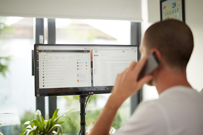 Man on a phone looking at a computer screen